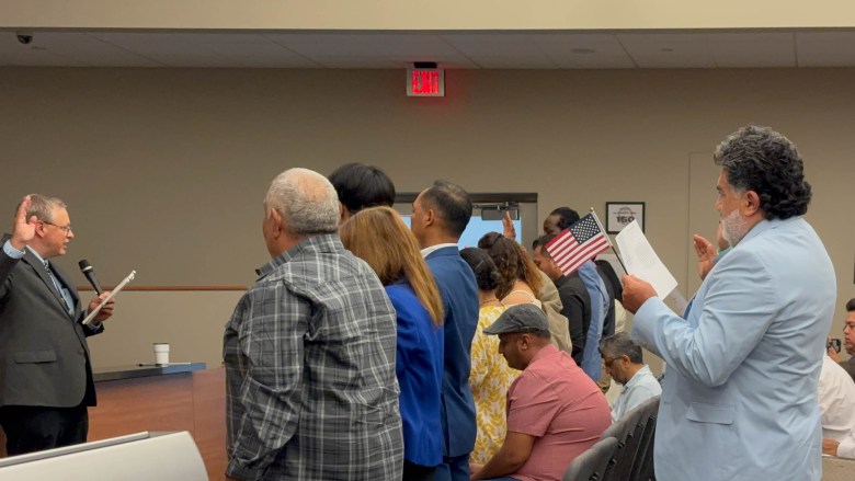 Individuals stand as they take an oath