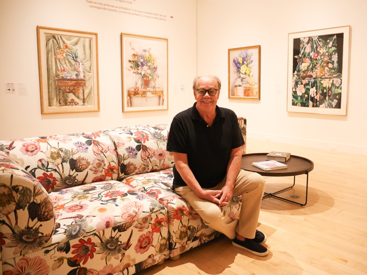 Patrick Gordon sitting on couch in front of paintings.