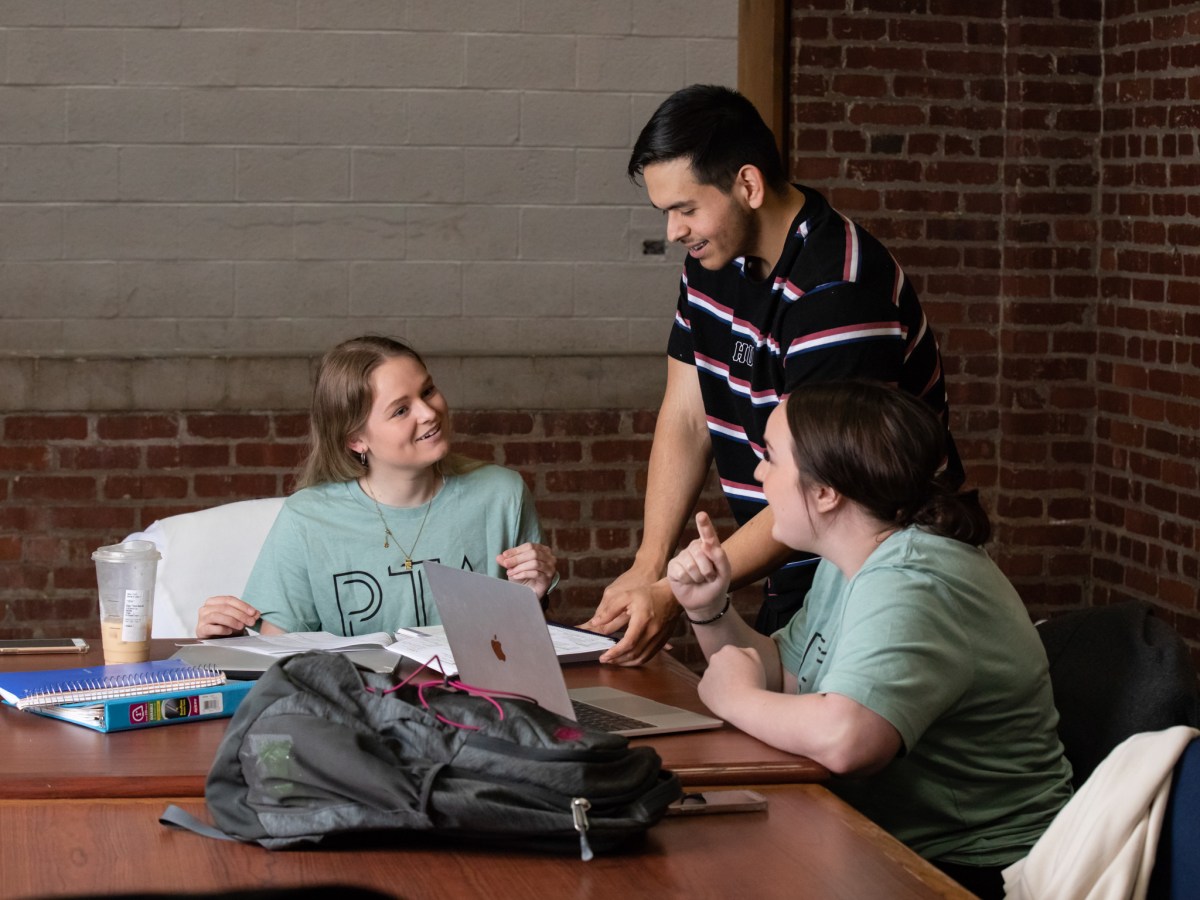 Students sitting at table looking at a laptop