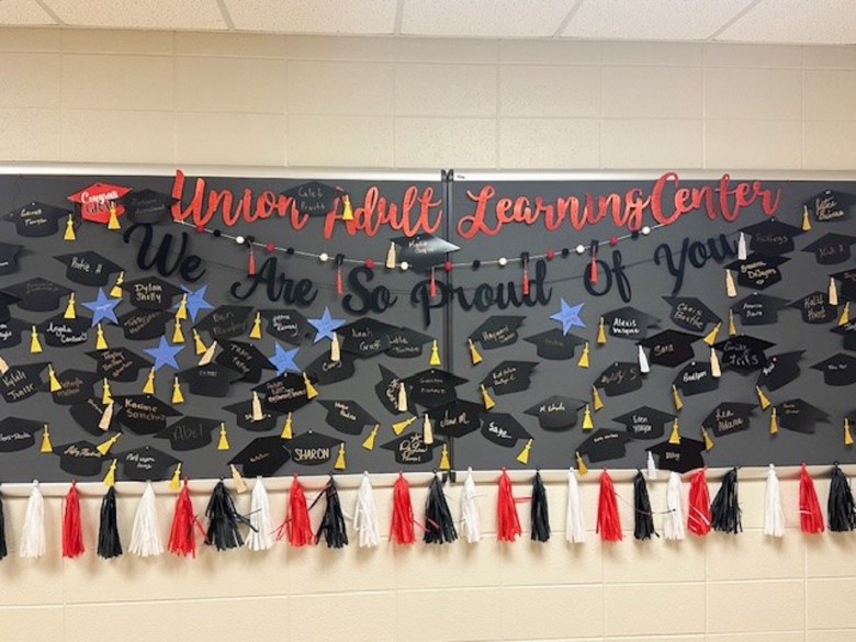 UALC's Celebration Board, pictured here in the 2024-2025 school year, displays a graduation cap for every program alumnus.