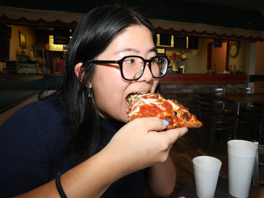Cost of living reporter Libby Hobbs eats a slice of La Roma's supreme pizza inside the restaurant at 6027 S. Sheridan Road.