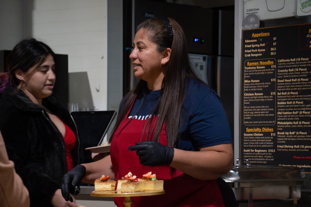 Lidia Nohemi Varela Suazo of Cakes by Mimi serves food during a El Programa de Lanzamiento graduation celebration at Mother Road Market on Dec. 16, 2025.