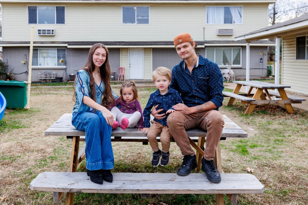 Man and woman sit with their children on picnic bench