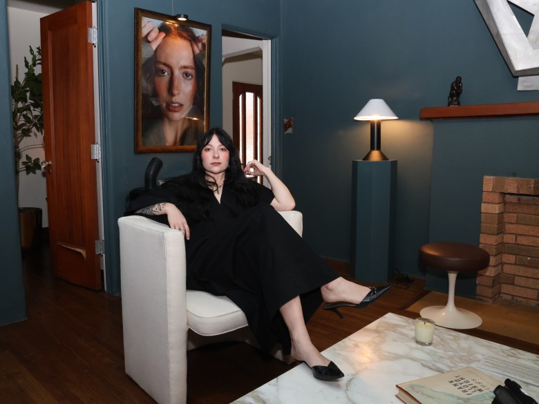 Woman sits in a chair in front of portraits