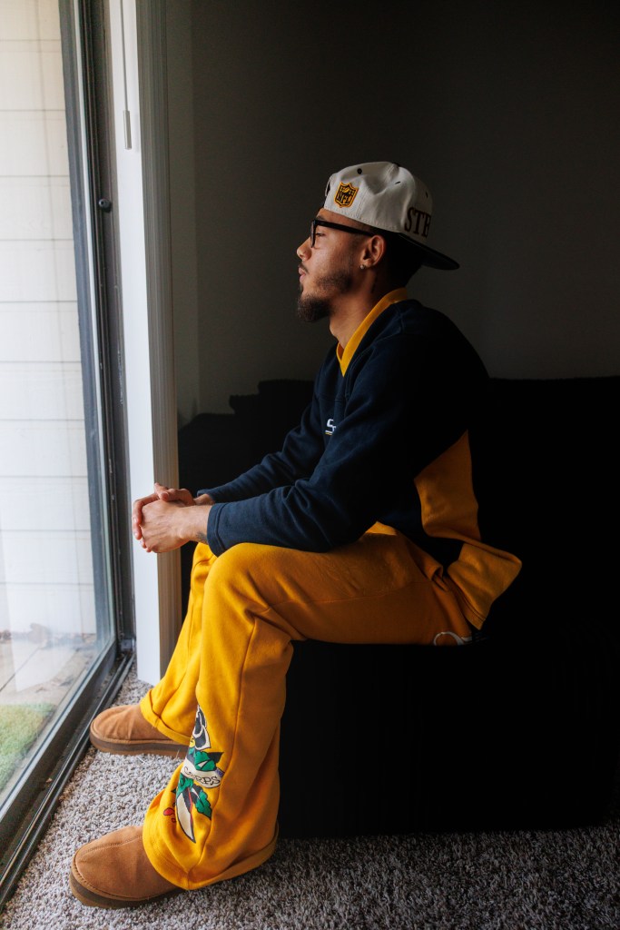 Man looks out window while sitting on bed