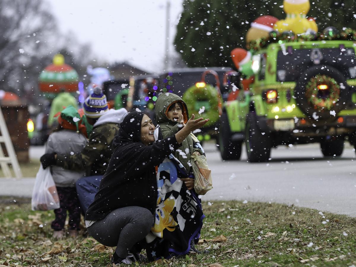 A family tries to catch fake snow falling from parade floats at the 2025 Glenpool BlackGold Christmas Sunday, Dec. 7, 2025. The parade started on 141st Street and ended near BlackGold Park in downtown Glenpool, Oklahoma.