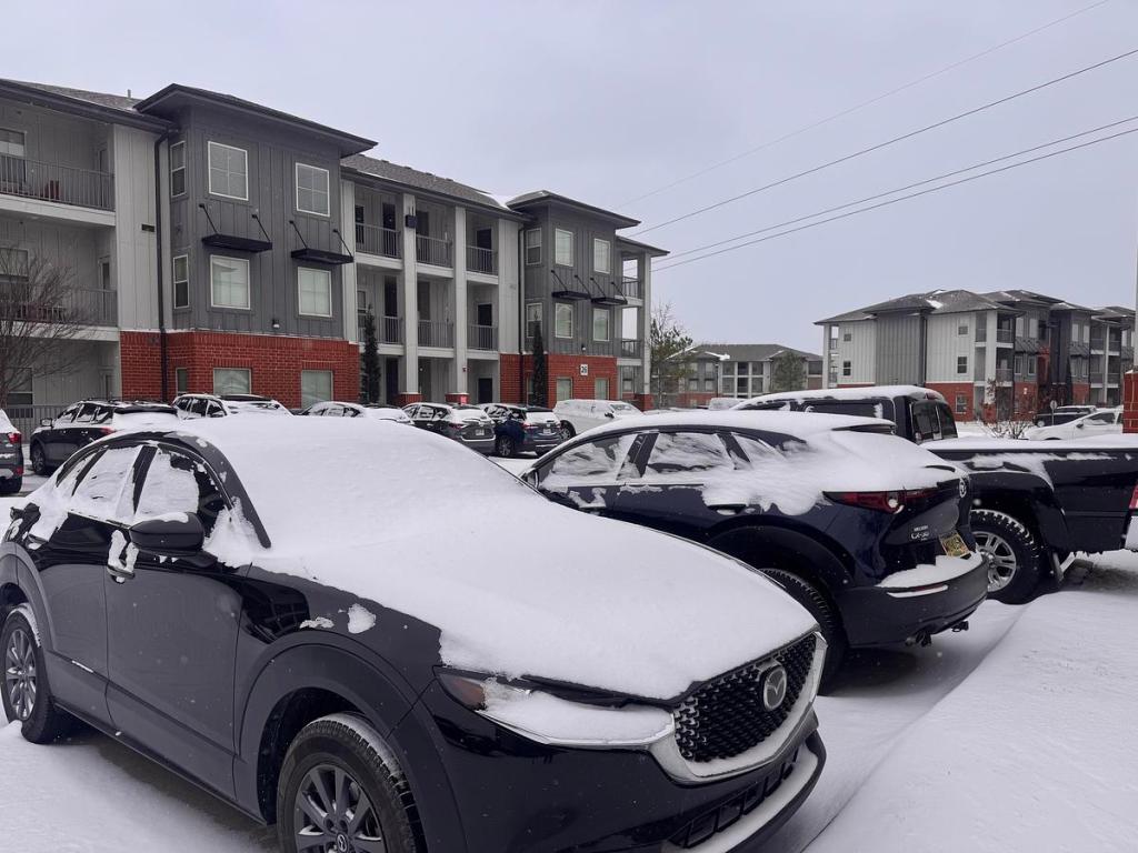 Snow covers cars in an apartment parking lot near 71st and Elwood Jan. 24, 2026.