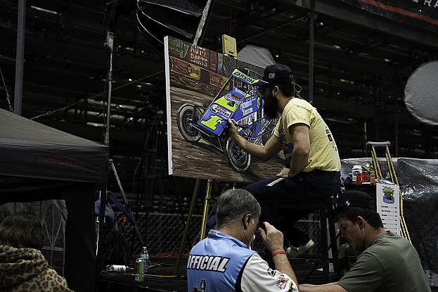 An artist puts final details on a painting that will be auctioned off Jan. 13, 2026, at the 2026 Chili Bowl Nationals. The event brings drivers, vendors and fans from across the country for a week of dirt-track racing action. 