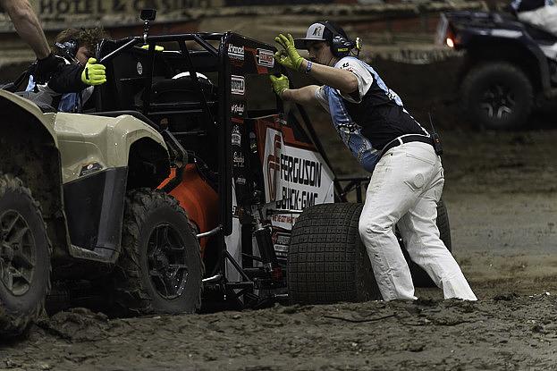 Race officials push a stuck race car from one of the track's banks Jan. 13, 2026 at the 2026 Chili Bowl Nationals. The event brings drivers, vendors and fans from across the country for a week of dirt-track racing action. 
