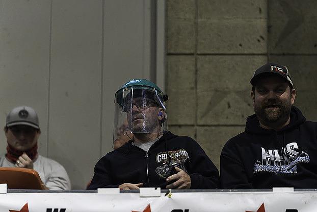 A fan wears a protective face mask while sitting in the front row adjacent to Turn 1 of the Chili Bowl's dirt track on Jan. 13, 2026, at the 2026 Chili Bowl Nationals. The event brings drivers, vendors and fans from across the country for a week of dirt-track racing action. 