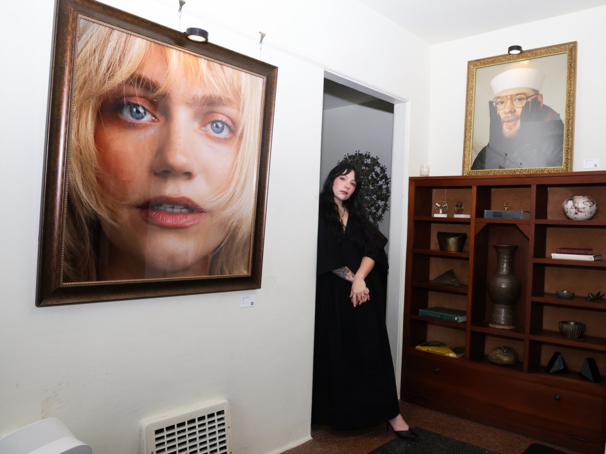 Woman standing inside studio next to portraits