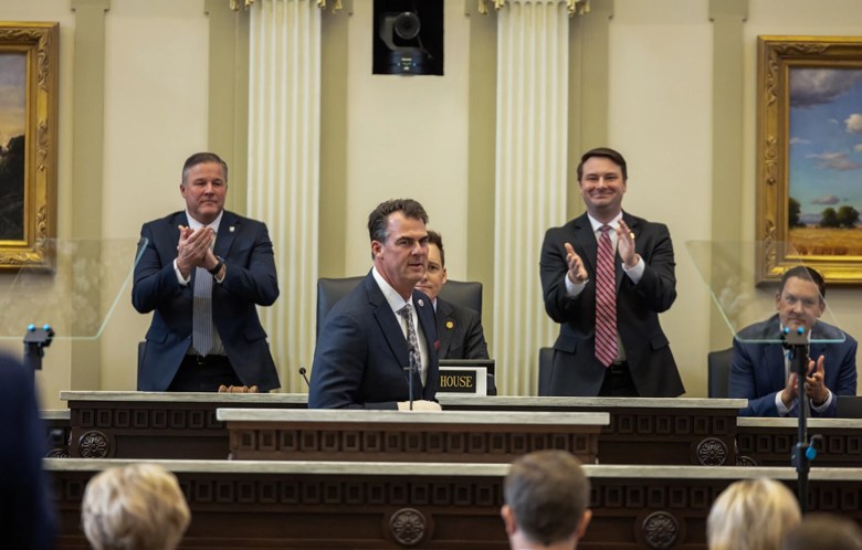 Senate Pro Tem Lonnie Paxton (left) and House Speaker Kyle Hilbert (right of center, in striped tie) applaud Gov. Kevin Stitt’s entrance to the House Chamber, moments before Stitt delivers his last annual State of the State Address.