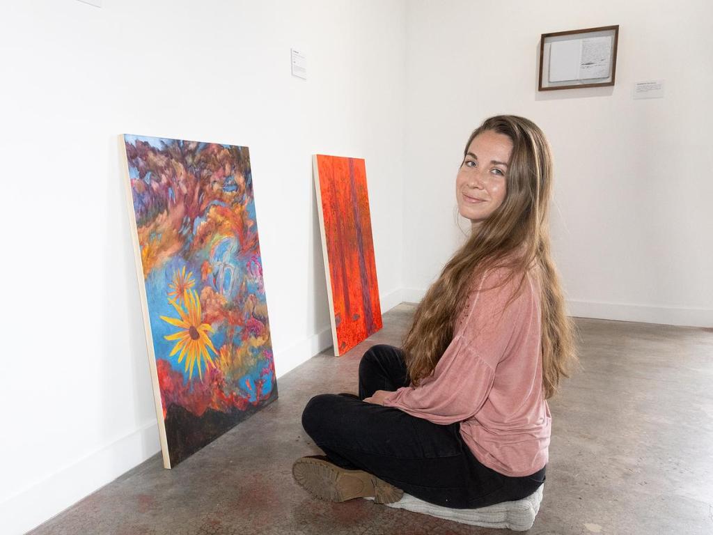 Liz Dueck sits with her paintings on display at Positive Space Tulsa March 11, 2026. The nature artist's exhibit "A Year of Embodied Art" runs through March 28.