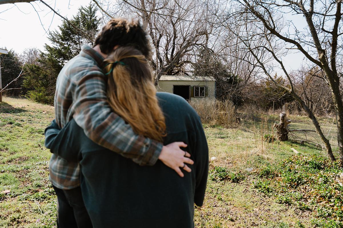 Brittany looks at the modest white house she lives in near Cement. Feeling suicidal late last year, Brittany called 988 — one of about 100,000 calls, texts or messages the service received last year.