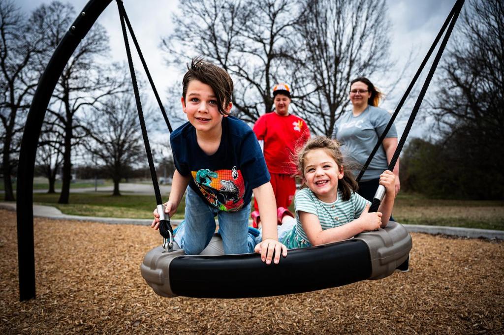 Jaxon Billings, left, and his sister Kelce smile on the swing while being pushed by their brother Trenton Maddox and mom Amanda Billings March 6, 2026. Since finding sobriety, Amanda's calendar has been full with parent-school meetings and student involvement at Tulsa Community College.