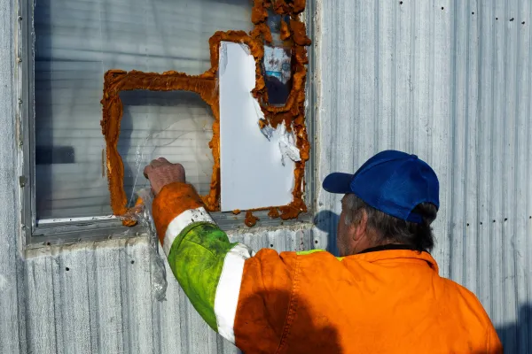 Frank Myers inspects a broken window at the mobile home he rents in December 2025.