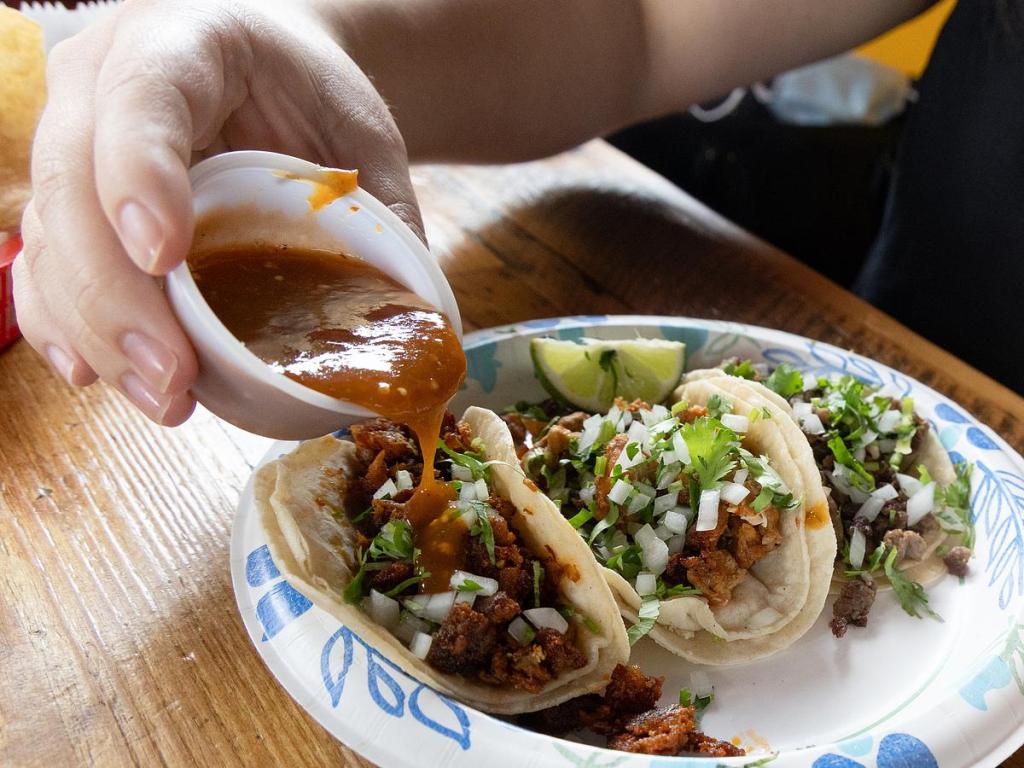 Adding the house salsa to tacos at Tacos Don Francisco, 4003 E. 11th St.