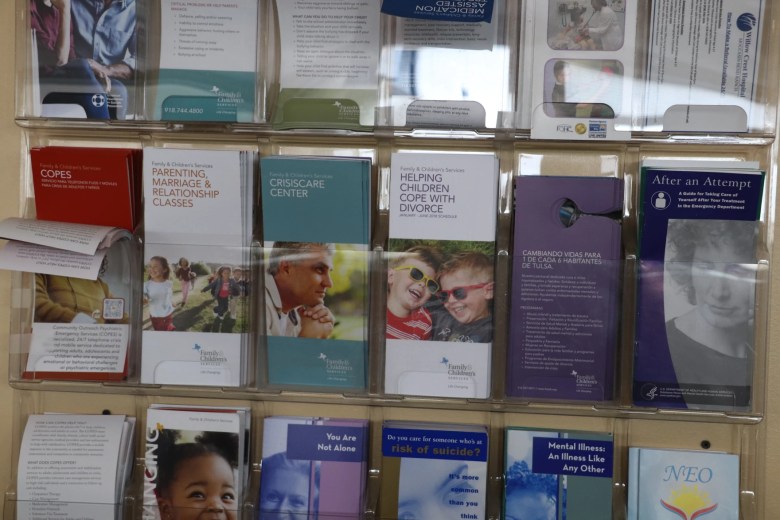 Pamphlets with information about mental health resources fill slotted containers on a wall inside the Family & Children’s Services’ call center.