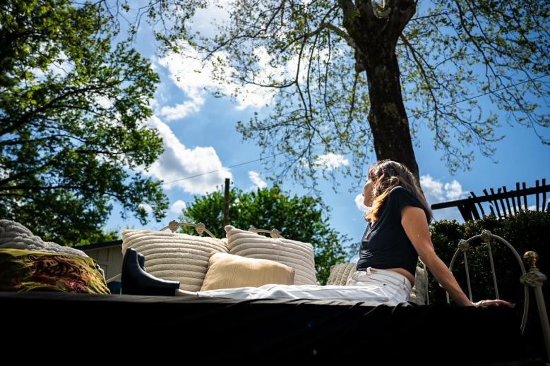 Lindsay sits on a couch in her backyard on Thursday, April 9, 2026. Lindsay is currently recovering from Kratom addiction and her cat has been instrumental in her recovery process.