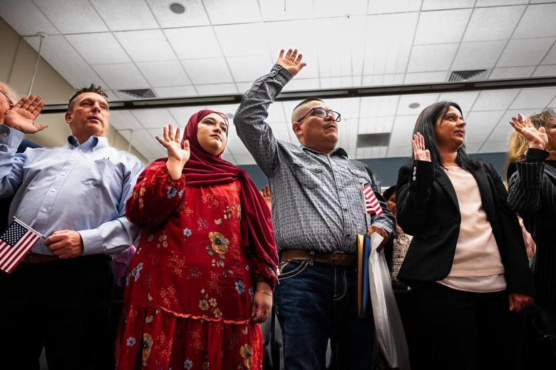 Jannat Khan from Pakistan, center, repeats the oath to The United States of America alongside her peers during a naturalization ceremony at City Hall on Thursday, April 9, 2026.