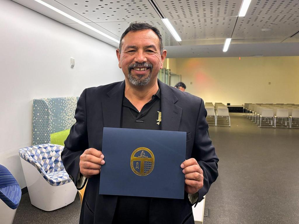 Julian Rodriguez holds his diploma at the Tomás Rivera awards ceremony on May 14, 2026, at the Central Library. He was recognized for his work as an educator.
