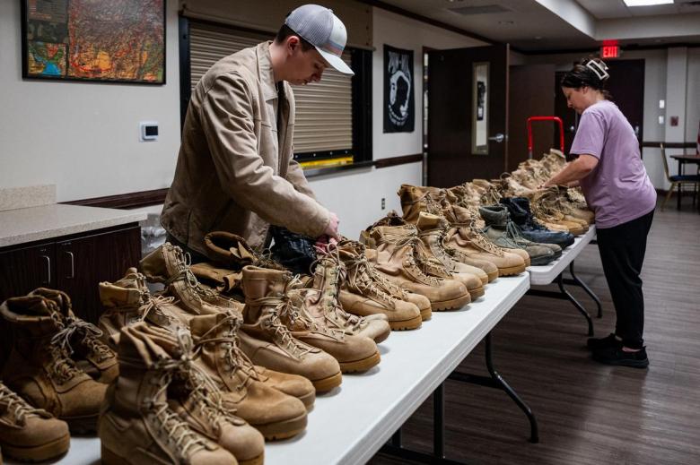Andrew Lucas, left, and Shyla B set up combat boots for the annual Memorial Day display at the Broken Arrow Veterans Center to represent fallen service members from Oklahoma.