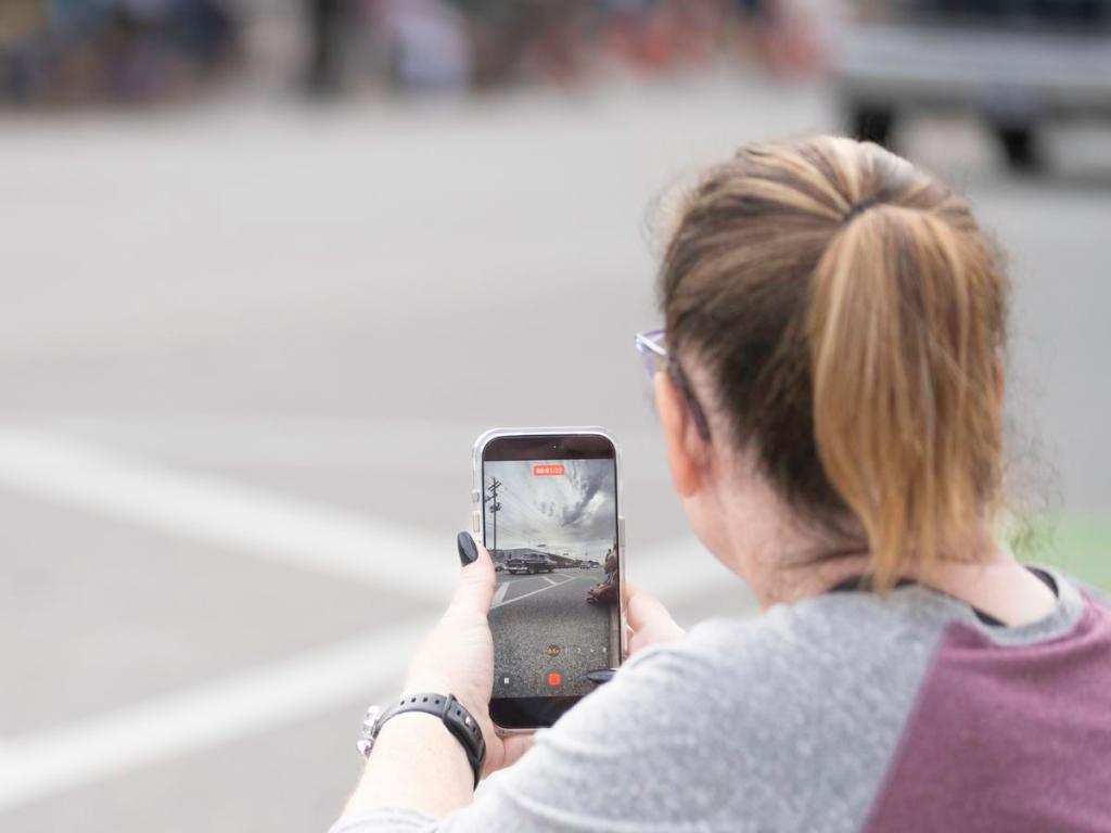 A bystander uses her phone to record a passing classic car during the Route 66 Capital Cruise on May 30, 2026. The cruise was an effort to break a world record for largest classic car cruise.