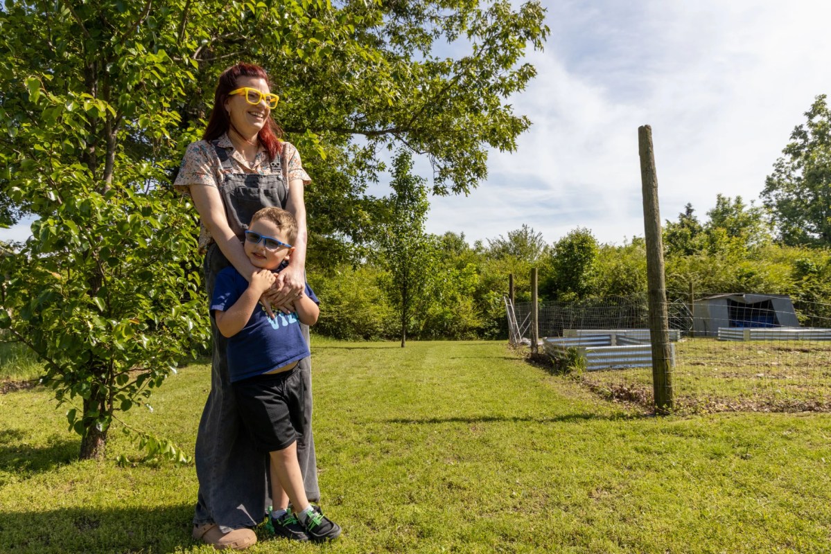 Ashley Caudle, a citizen of the Cherokee Nation, wraps her arms around her son, Elliot, next to her garden in Stilwell, Oklahoma, on May 1, 2026. Multiple generations of her family have struggled with substance abuse, and she has looked to her culture as a way to heal. “Addiction is not linear, and it doesn't affect just the addict," Caudle said. "It affects the daughters and the brothers and the support.”