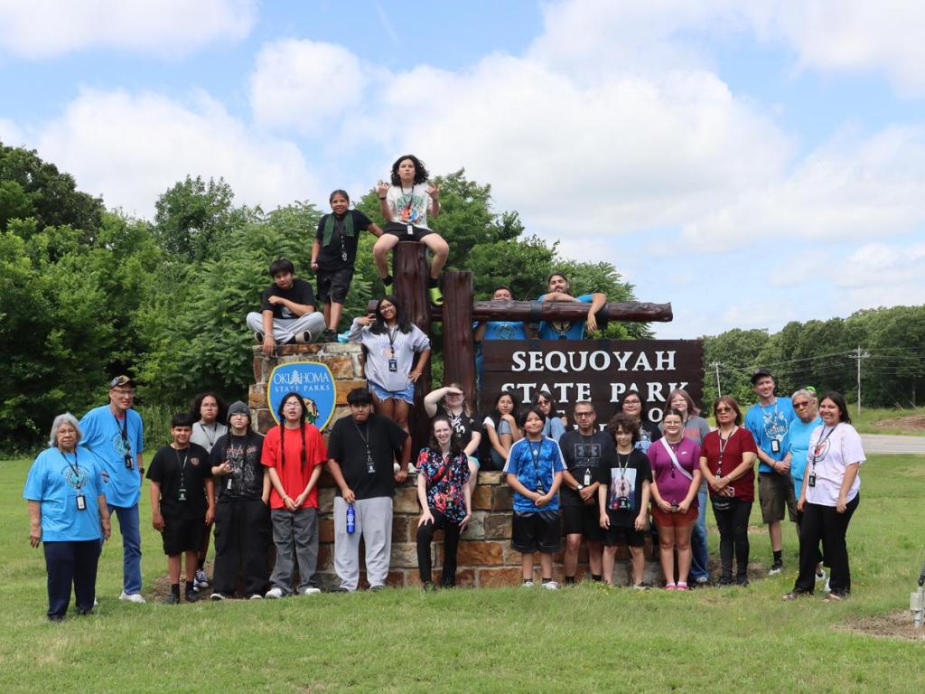 Participants of Muscogee Nation Language Department's adult language camp gather at the Sequoyah State Park sign on June 11, 2026.