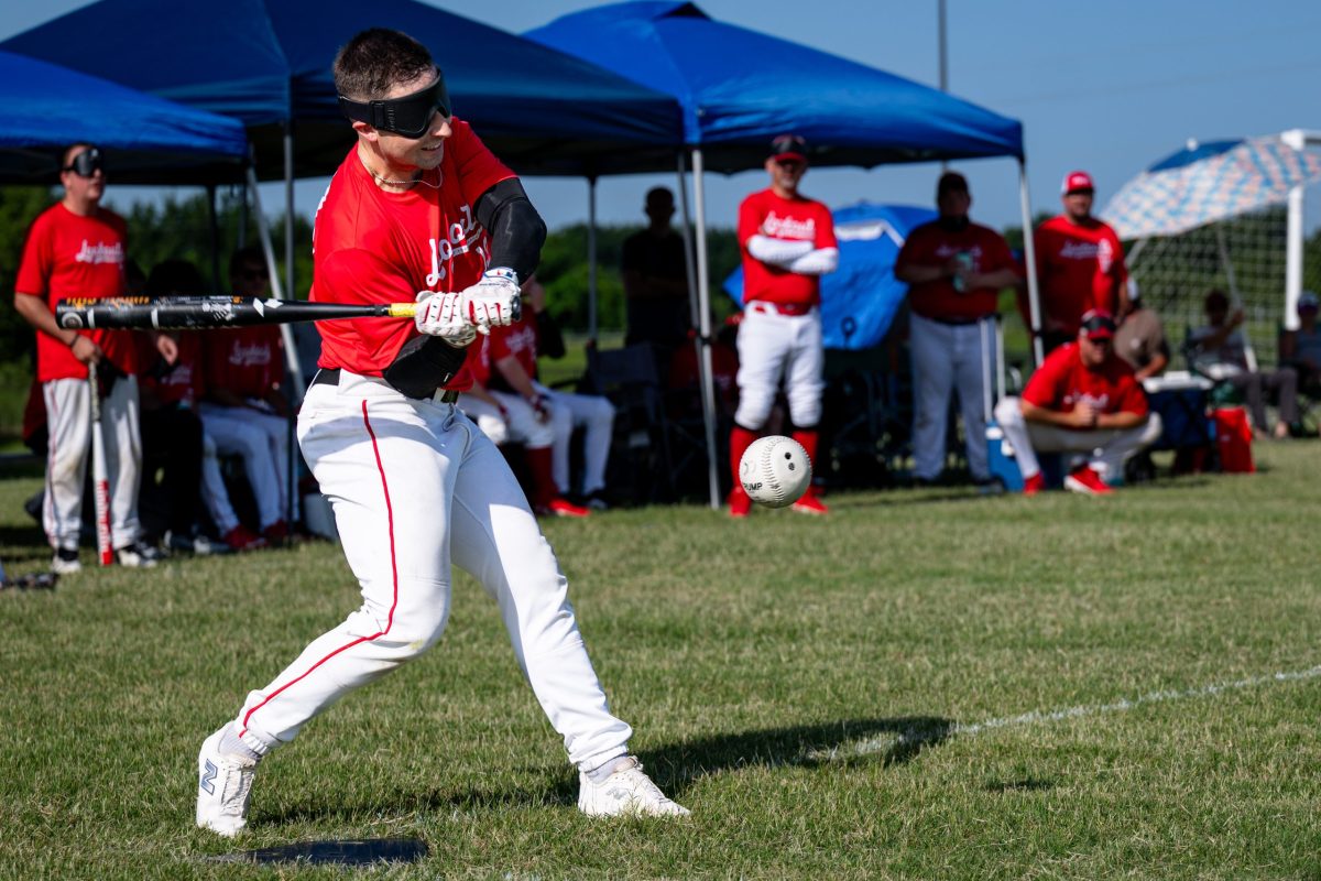 A beep ball player swings at a pitch while blindfolded