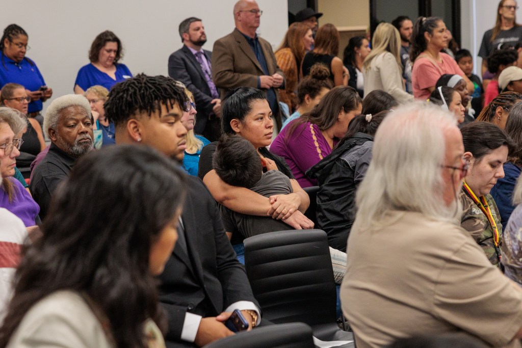 woman holds child while listening in audience