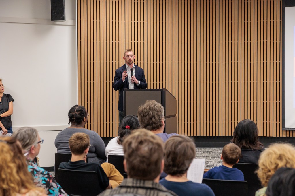 man addresses audience at library